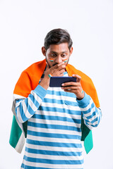 young indian man celebrating independence day or republic day and using smartphone