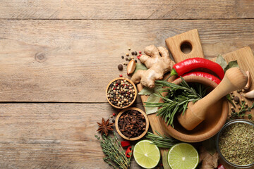 Flat lay composition with different natural spices and herbs on wooden table, space for text