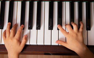 Selective focus to kids fingers on piano, top view. Learning music concept
