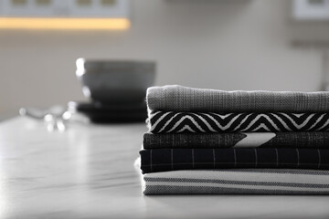 Stack of soft kitchen towels on white table indoors, space for text