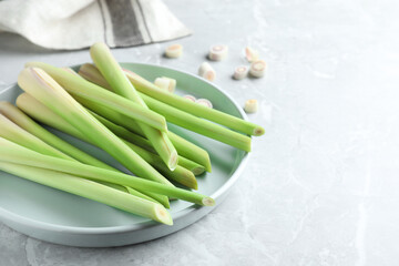 Plate with fresh lemongrass stalks on light grey marble table, closeup. Space for text