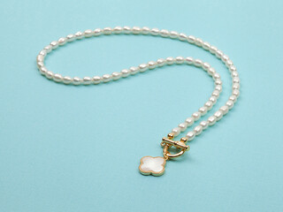 Luxury elegant baroque pearl necklace with pendant on bright turquoise textured background