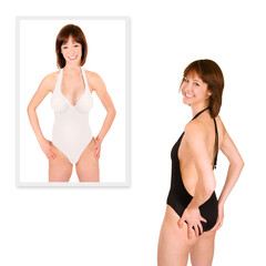 Rear view of a beautiful young woman wearing a black bathing suit in front of a swimsuit photo of herself, isolated on white studio background