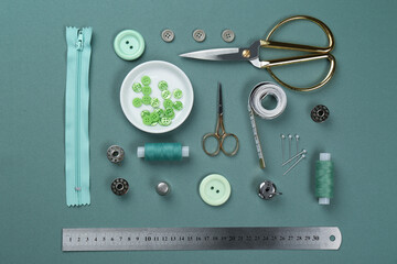 Flat lay composition with different sewing supplies on green fabric