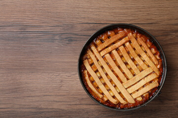 Delicious apricot pie in baking dish on wooden table, top view. Space for text