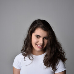 Fototapeta premium Close up portrait of young woman with natural brown hair, over the top facial expressions on light grey studio background.