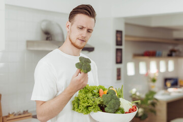 Young man don't want to eat vegatables. Man don't want to eat Broccoli.