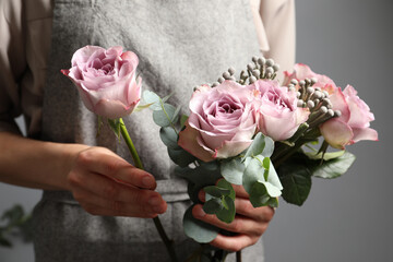 Obraz na płótnie Canvas Florist creating beautiful bouquet with roses indoors, closeup