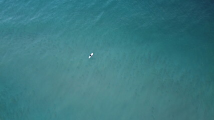 Lone surfer riding out into the sea waiting to catch waves crashing against the beach, summer vibes, coastal Victoria, Great Ocean Road, Australia