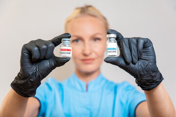 Covid-19 vaccination. A doctor in medical gloves holds two ampoules with a vaccine against coronavirus. The concept of choice and the dangers of vaccination