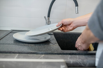 A gray-haired man cleaning the fridge in the kitchen