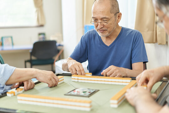 介護施設のレクリエーションルームで麻雀をする高齢者