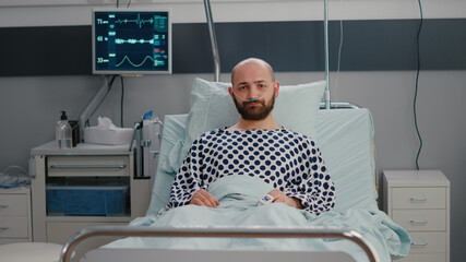 Potrait of sad sick man wearing nasal oxygen tube lying in bad looking into camera during sickness...