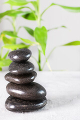 Black zen stones in a stack on white background with bamboo..