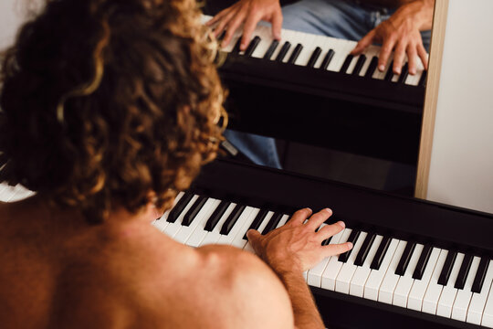 Unrecognizable man playing piano at home