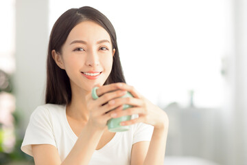 beautiful young woman holding a cup of tea in living room at home