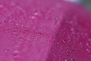 Rain droplets on a magentas waterproof fabric  background,close up
