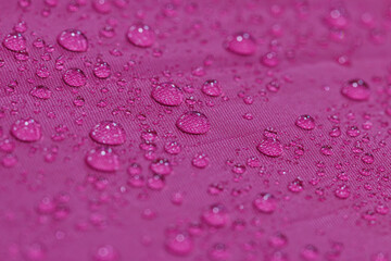 Rain droplets on a magentas waterproof fabric  background,close up