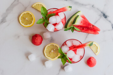 Summer cold drink with watermelon, ice and lemon on white marble background, top view, selective focus