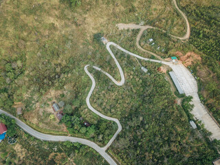 Aerial view of the curved road cut throug the forest on Doi Pha Tang mountains in Northern region of Thailand.