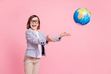 Fototapeta premium Portrait of attractive cheerful girl throwing globe travel journey having fun isolated over pink pastel color background