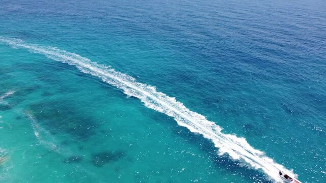 Drone view of a boat the blue clear waters. Top view of a white boat sailing to the blue sea. Large speed boat moving at high speed. Travel - image