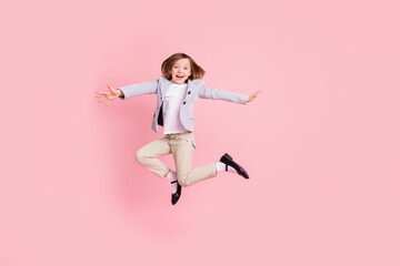 Full size photo of impressed small girl jump wear striped blazer trousers shoes isolated on pastel pink color background
