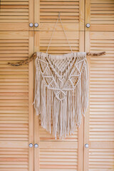 Macrame wall hanging decoration on wooden background.