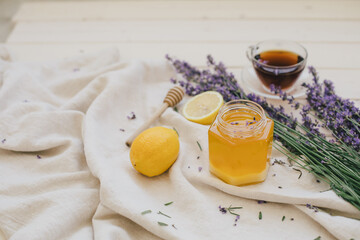 Jar with honey, herbal tea, lemons and bunch of lavender on wooden background. Healthy food.