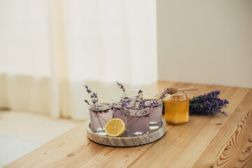 Fresh lavender lemonade and jar with honey on a kitchen table.