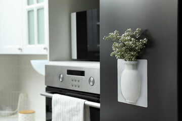 Silicone vase with beautiful gypsophila flowers on fridge in kitchen, space for text