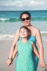 Happy mother with smiling little daughter on a beach