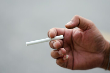 Men hand holding a cigarette on a white background close-up.