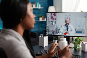 Afro american patient discussing pills treatment against respiratory sickness with therapist during online videocall meeting telehealth. Doctor explaining disease diagnosis after medicine test