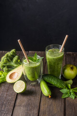 Fresh green smoothie in glass on wooden table, closeup.  Detox diet concept: green vegetables on rustic table. Clean eating, alkaline diet, weight loss food concept.