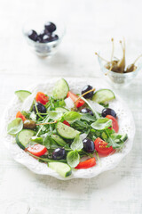 Salad with black Olives, cherry Tomatoes, Cucumber and Rocket on bright Background. Close up.	