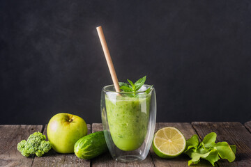 Fresh green smoothie in glass on wooden table, closeup.  Detox diet concept: green vegetables on rustic table. Clean eating, alkaline diet, weight loss food concept.