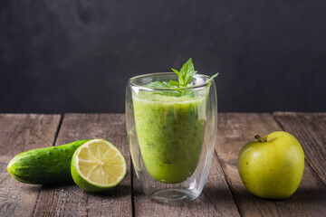 Fresh green smoothie in glass on wooden table, closeup.  Detox diet concept: green vegetables on rustic table. Clean eating, alkaline diet, weight loss food concept.