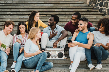 Diverse friends with smartphones and boombox chatting on stairs