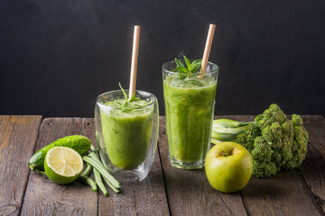 Fresh green smoothie in glass on wooden table, closeup.  Detox diet concept: green vegetables on rustic table. Clean eating, alkaline diet, weight loss food concept.