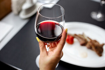 Close up of red wine in woman hand at the restaurant