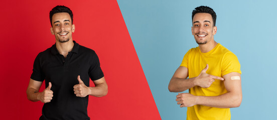 Covid-19 vaccination. Happy smiling Latino man posing isolated on blue and red studio background....