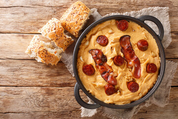 Spanish food Gachas of pea flour with paprika served with bacon and chorizo close-up in a pan on the table. horizontal top view from above