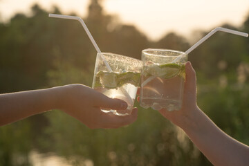 two hands hold glasses with lemonade. refreshing drinks with lime and mint.