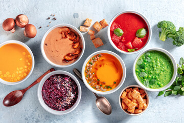 Colorful vegetable soups, vegan diet. Pumpkin, mushroom, beetroot, tomato, sweet corn and green pea pureed creams, shot from the top with ingredients