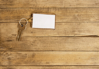 Top view of a key with a keychain on wooden background