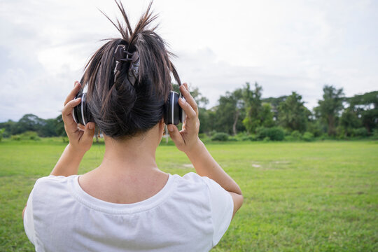 Cute asian woman listen to music and holding white headphone, back shot.