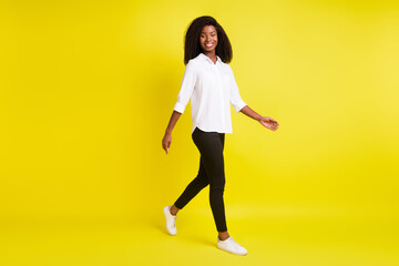 Full length body size photo smiling girl walking forward wearing white shirt isolated bright yellow color background