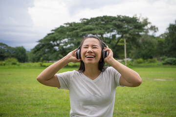 Good-looking asian young woman with no makeup having fun with favorite music outdoor.