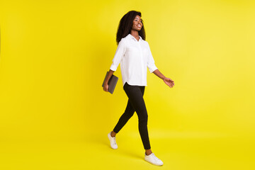 Fototapeta na wymiar Full length body size photo smiling girl walking forward keeping laptop looking blank space isolated bright yellow color background